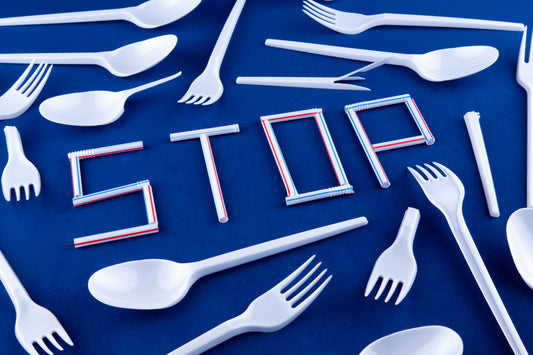 Stopp an Plastikstrohhalmen, umgeben von Plastikbesteck